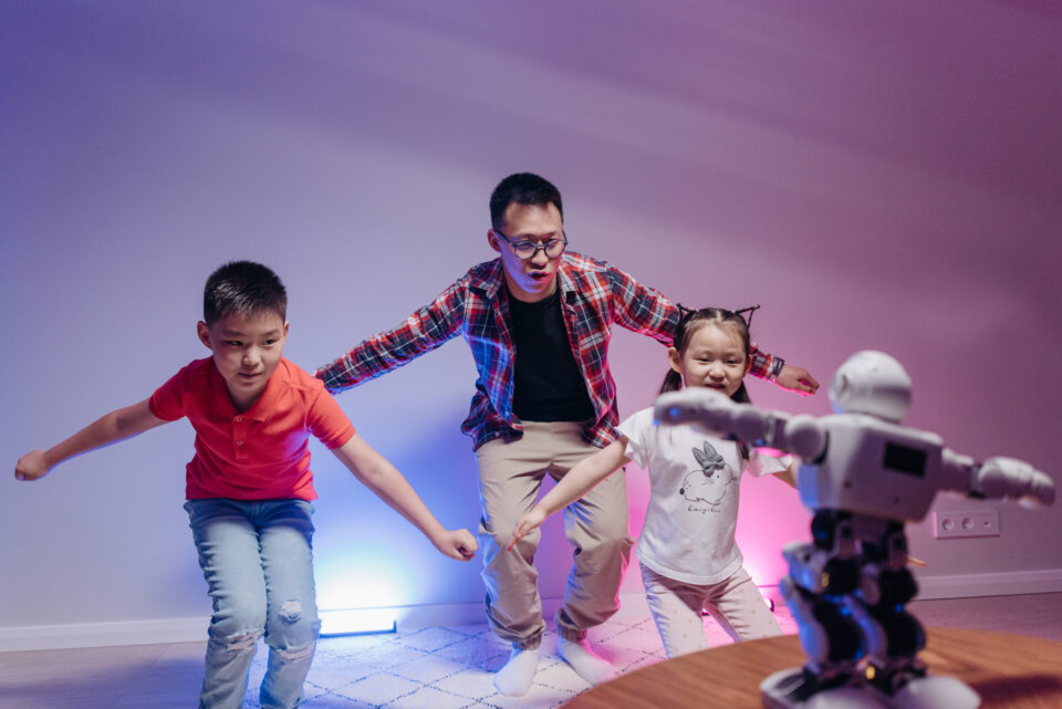 A man and two children imitating a dancing toy robot