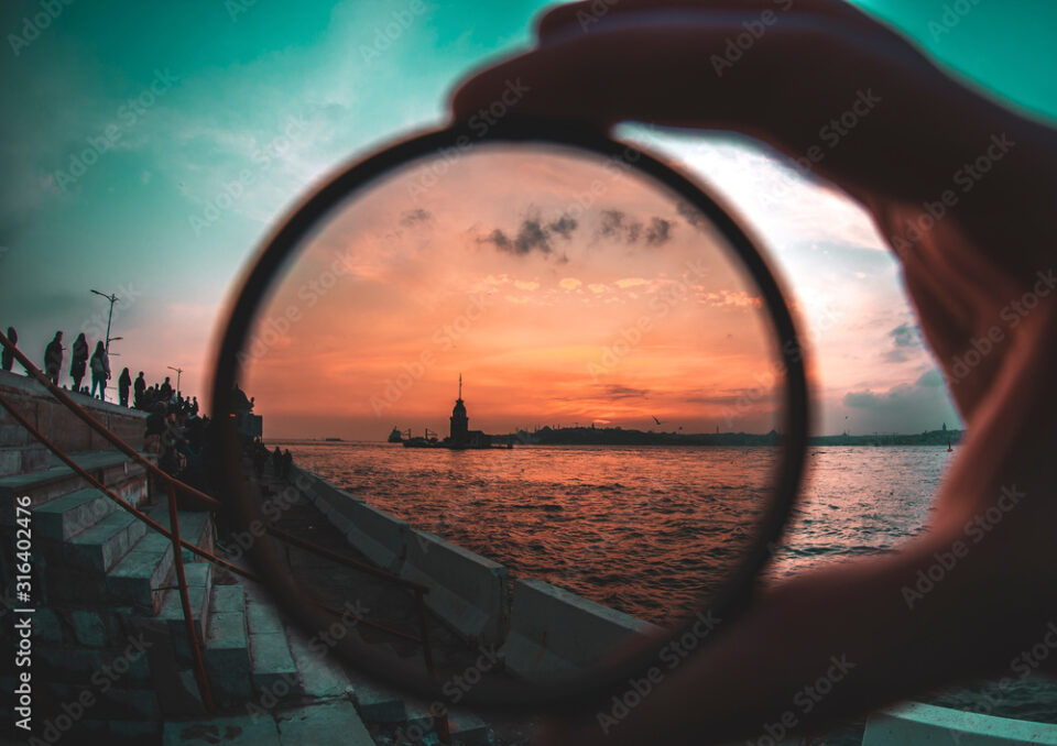 a man holding a photo filter with backgorund of Maiden Tower during sunset