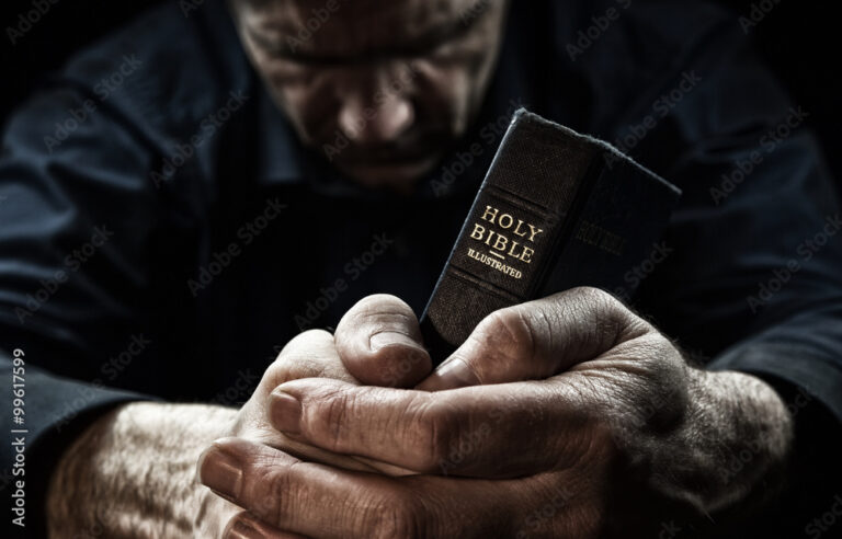 A Man praying holding a Holy Bible.