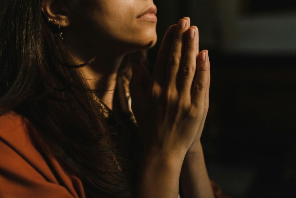 A person in orange shirt with hands together