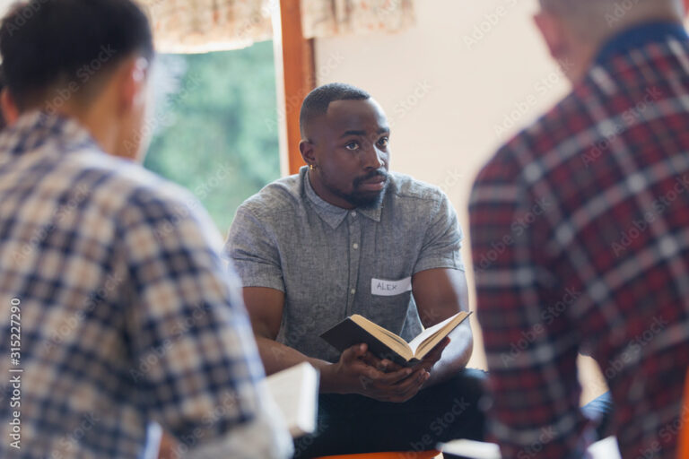 Attentive young man with bible in prayer group