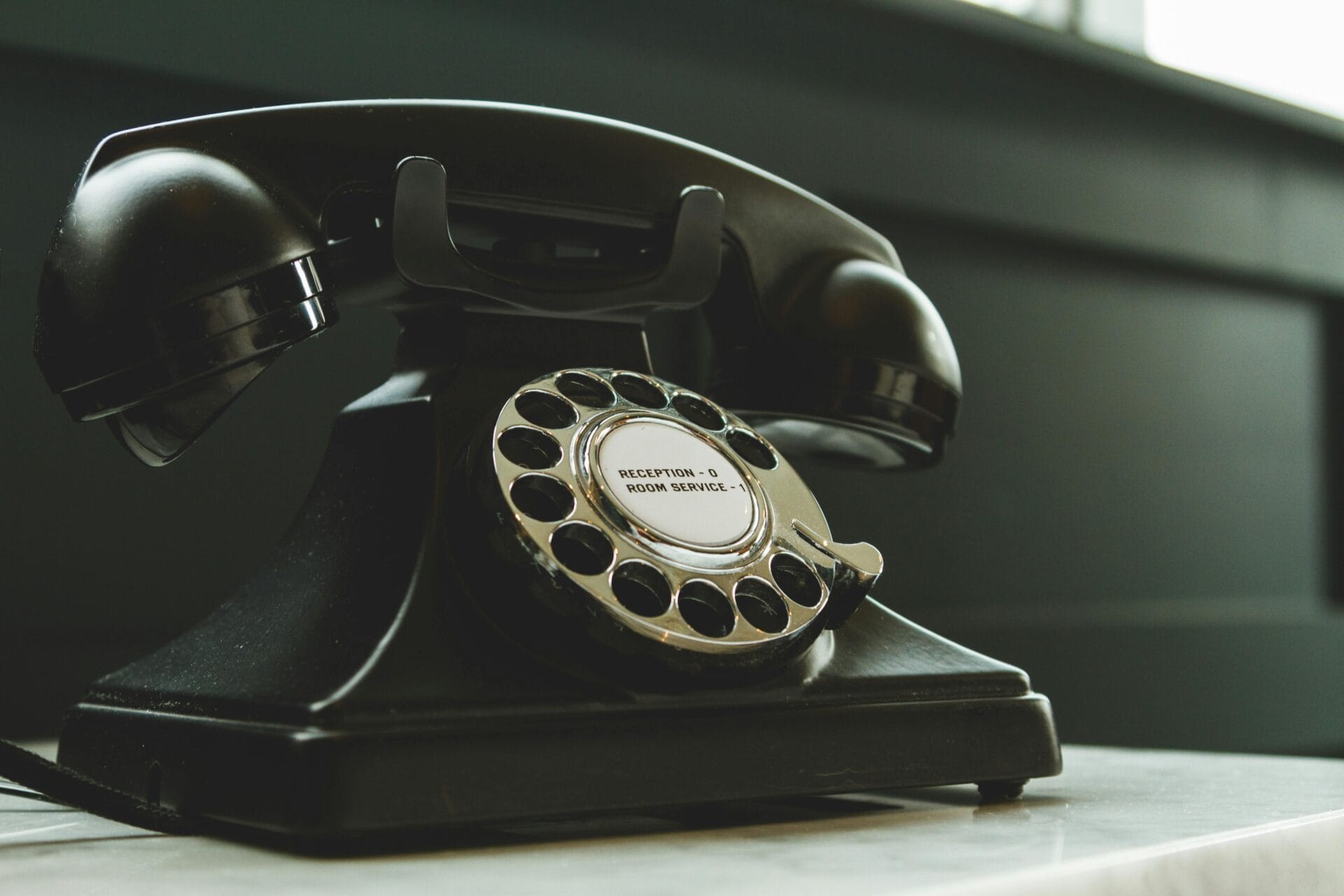 Black rotary telephone on white surface