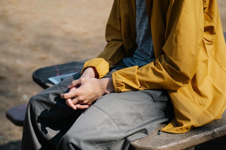 Crop person sitting on wooden bench