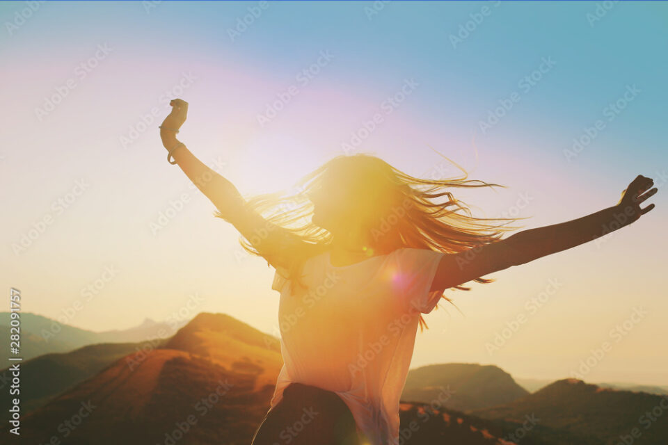 Girl on a background of mountains joyful spread her arms dancing at a height 2