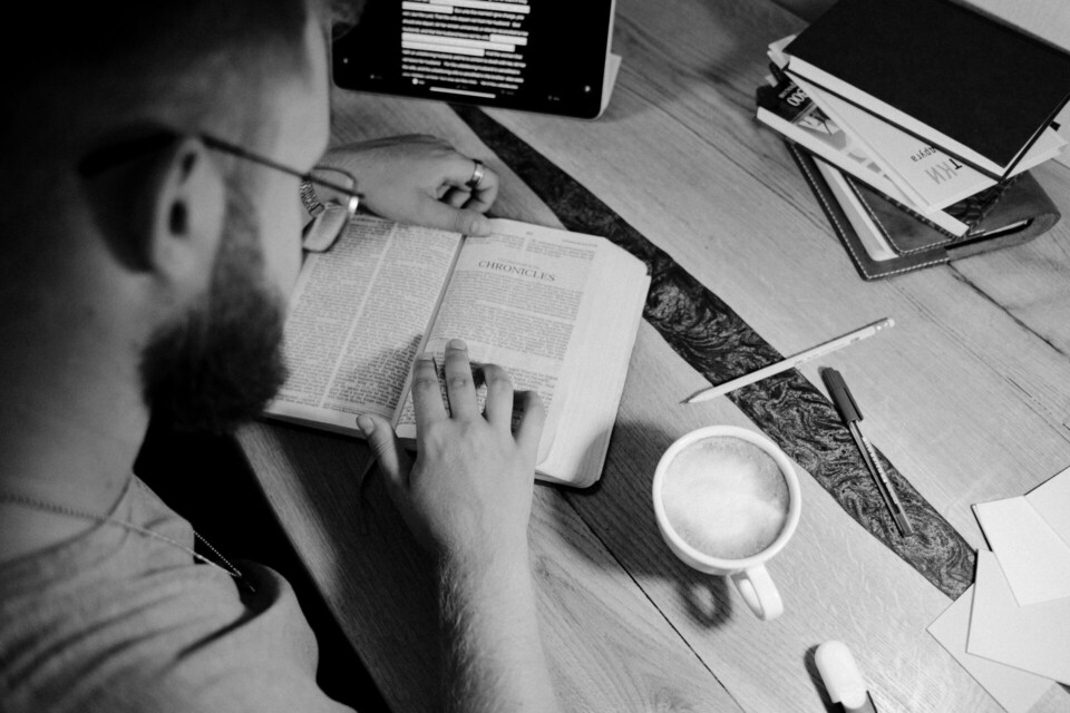 Grayscale photo of a person reading a bible