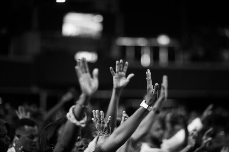 Grayscale photography of people raising hands