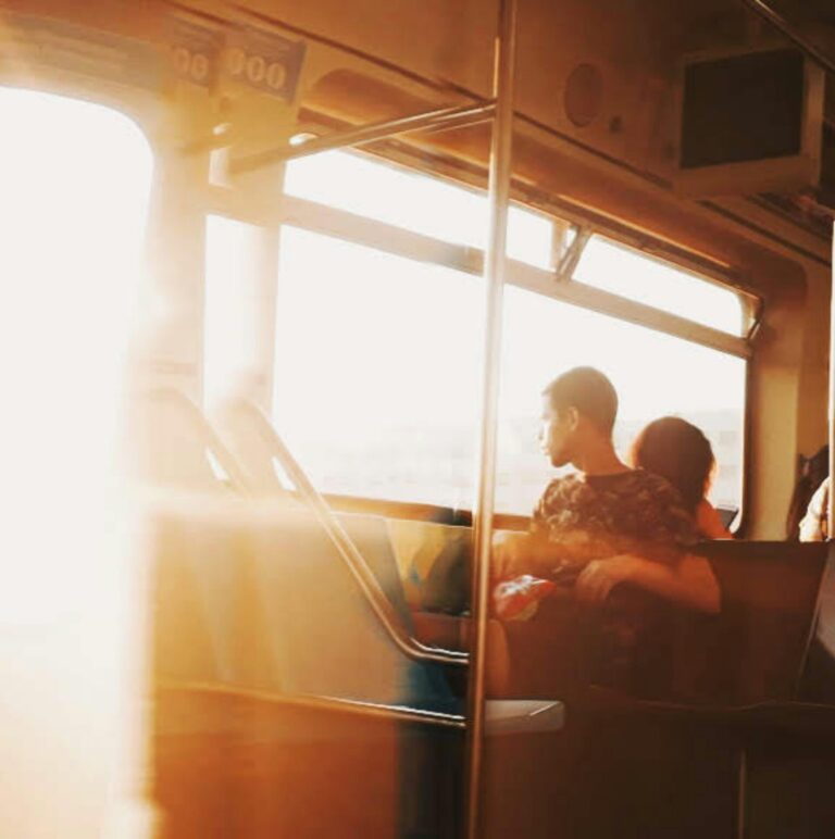 Man sitting on public transportation seat beside window