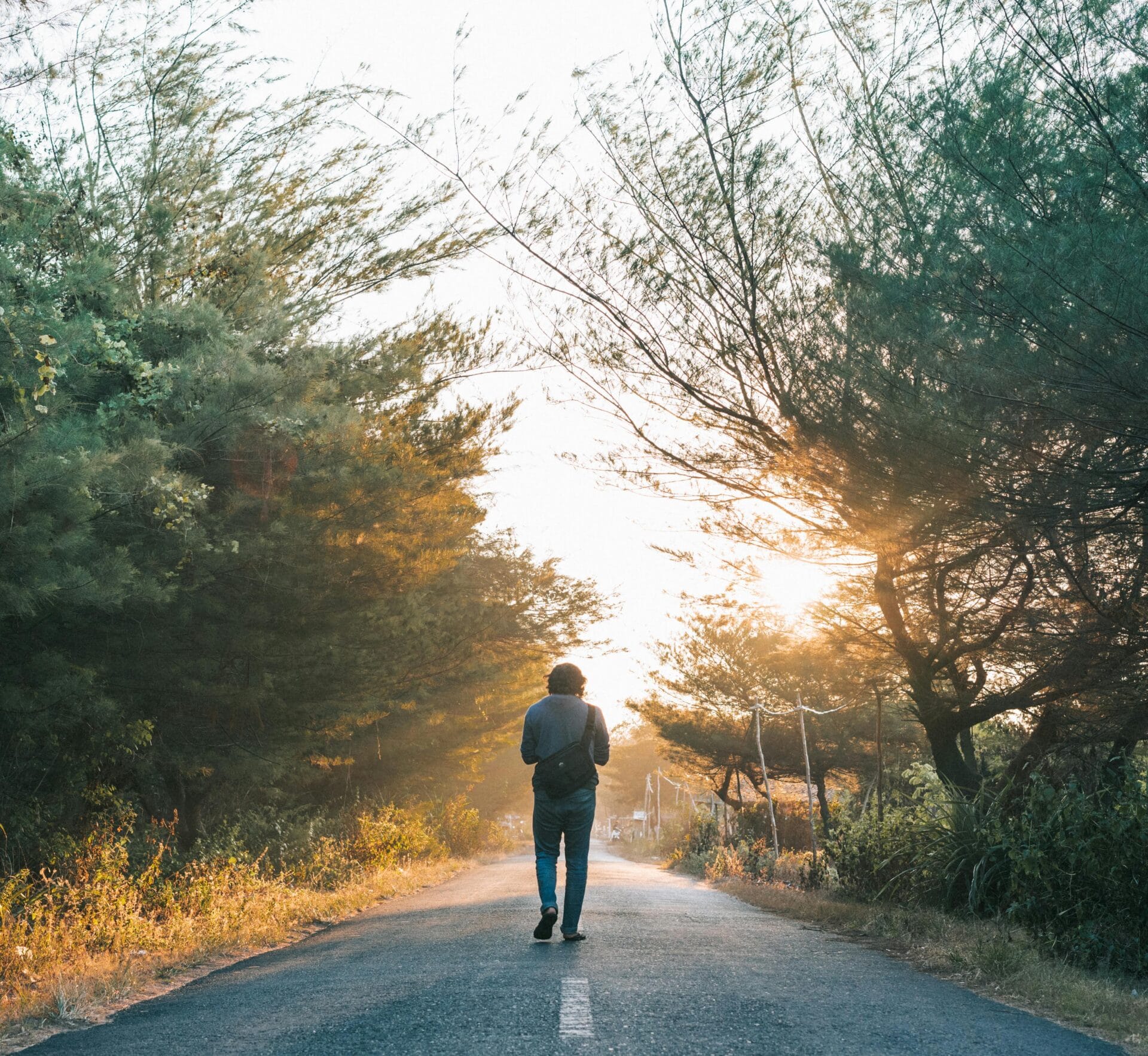 Man walking on the gray asphalt road
