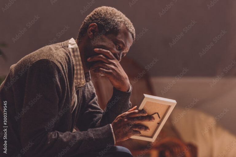 senior, depressed african american man looking at photo frame