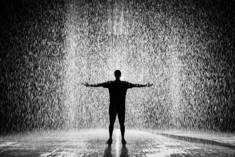 Silhouette and grayscale photography of man standing under the rain