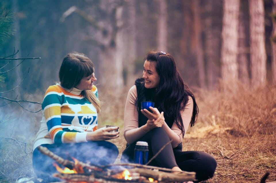 Two women sitting on ground near bonfire