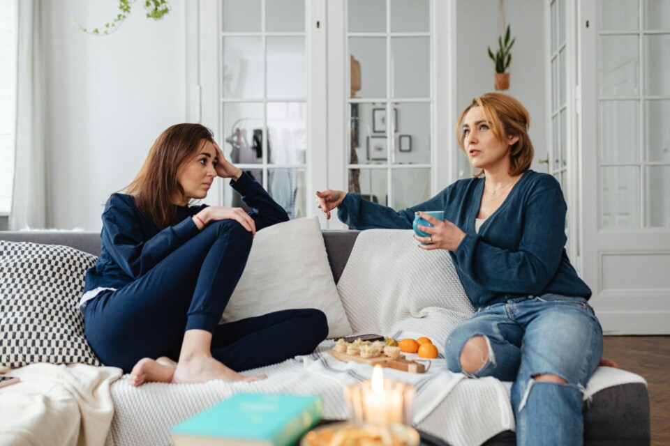 Two women sitting while talking on a sofa