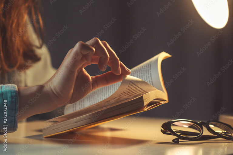 Woman reading book at evening at home close up