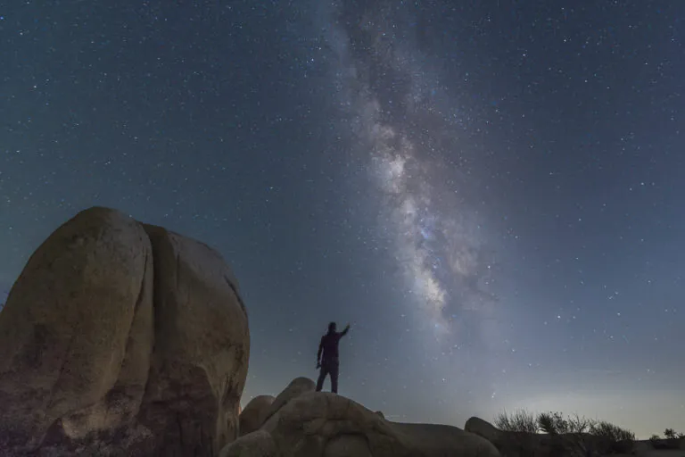 A person standing on a rock under a starry night sky