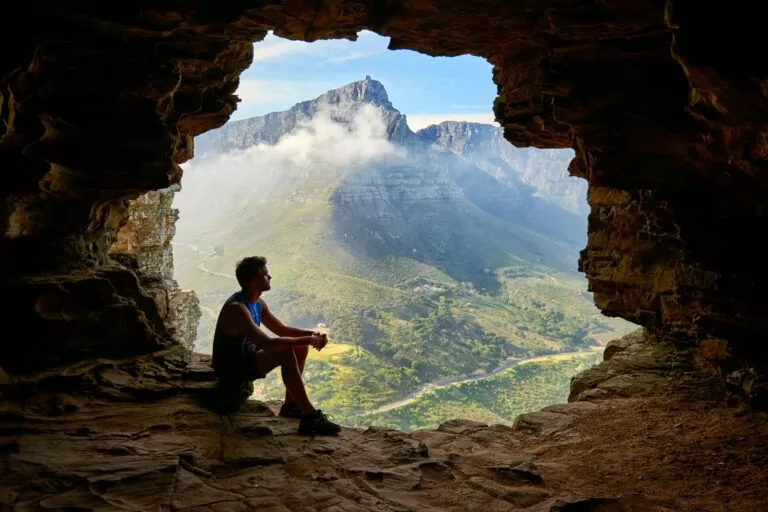 Photo of man sitting on a cave