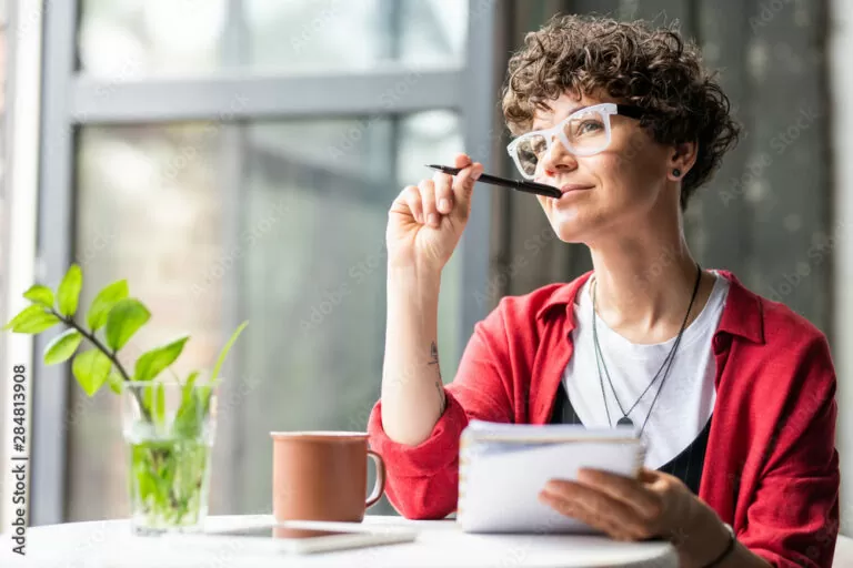 Young pensive female in eyeglasses thinking of new creative ideas